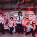 The photo shows the visual kei band GERTENA in a space with an industrial feel, decorated with a multitude of red strings and small pieces of white papers and kanji on them. All band members are dressed in black and white clothing decorated with ink splats.