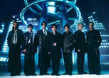 Photo of the seven members of PSYCHIC FEVER from EXILE TRIBE standing next to each other in a futuristic setting. They are dressed in dark clothing, inspired by suits, but with different elements showing their personalities, from leather jackets to extra accessories.