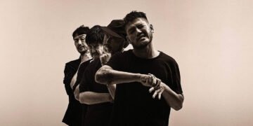 A monochromatic photo of the four members of the Japanese instrumental rock band toe, posing behind each other with various (dramatic) facial expressions, with the eyes closed. All are dressed in dark/black clothing.