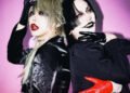 Photo of visual kei artists Aryu (THE DEVIL INSIDE) and Tsuzuku (tzkwym) standing next to each other with their backs to each other. They both look toward the camera. Both are fully dressed in black clothing, but with different garments and fabrics, wearing gloves, coloured lenses and topped off with full face of makeup. While Tsuzuku wears one red glove, Aryu wears red lipstick. © Killing Daze Management