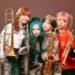 Band photo of the four women of brass band MOS. They all have colourful hairstyles and are dressed differently, showing off their individuality. Photography by Youhei Nobe (@/youhei_nobe on Instagram)