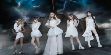 The photo features the five women of LOVEBITES posing together while standing on a ship and dark clouds with lightning on the background. They are uniformly dressed in white/off-white with gold elements outfits, each incorporating their personal style.