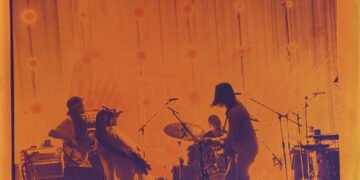 A photo of kanekoayano performing on stage with an orange filter, making it seem that the photo is taken in black-and-white on film. © Photography: Kiyoe Ozawa