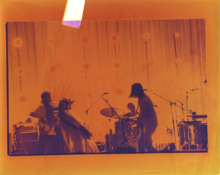 A photo of kanekoayano performing on stage with an orange filter, making it seem that the photo is taken in black-and-white on film. © Photography: Kiyoe Ozawa