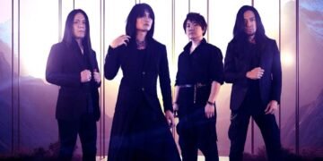 Photo of the four-piece alternative metal band Esprit D'Air standing side by side on a location with a mountain range on the background. All the members are dressed in black clothing, with gothic and metal elements.