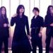 Photo of the four-piece alternative metal band Esprit D'Air standing side by side on a location with a mountain range on the background. All the members are dressed in black clothing, with gothic and metal elements.