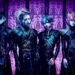 The photo features the four members of JILUKA, dressed in distinct dark, gothic attire with silver face jewelry (such as a chin, eye or ear piece) posing against a purple gothic-themed screen.