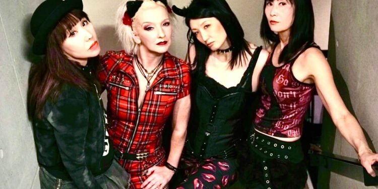 The photo features the four members of MIKABOMB (Also written as MIKA BOMB), all dressed in an alternative fashion style, wearing punk-inspired attire. They are standing close together on a flight of stairs.