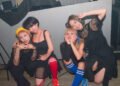 The four members of cheer punk band Ni-hao!!!! posing together before or after a show. They are all dressed in black clothing and wear coloured socks.  © Photo by Yukiko Ono