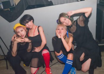 The four members of cheer punk band Ni-hao!!!! posing together before or after a show. They are all dressed in black clothing and wear coloured socks.  © Photo by Yukiko Ono