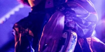 Focus on Mari of TsuShiMaMiRe on stage of Musicon in The Hague, while she is playing her guitar. De full focus goes onto her hands. The stage lighting is at full power, making the musician glow a bit. Photography: Francisca Hagen (AVO Magazine)